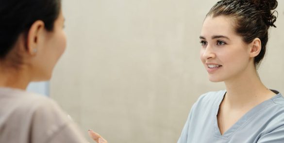 Nurse in conversation with patient at a medical reception desk, emphasizing care and support.