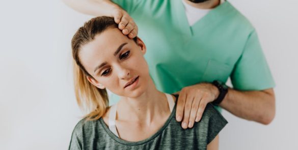 Positive male massage therapist gently massaging female patients neck and shoulders while stretching neck muscles