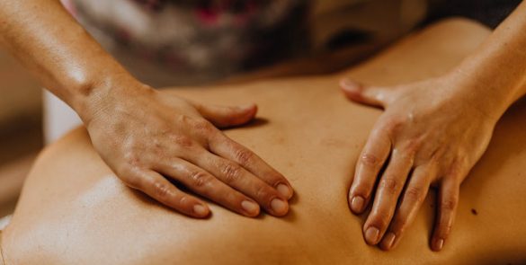 Close-up of hands giving a soothing back massage in a calm setting.